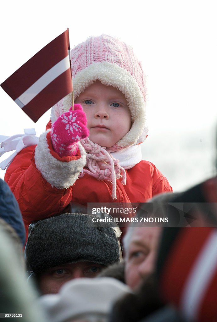 A girl holds holds a Latvian flag during