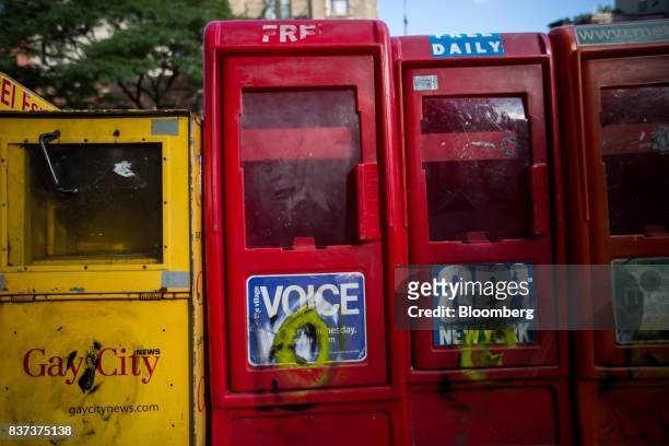 An empty distribution box for The Village Voice, second left, is seen in the East Village neighborhood of New York, U.S., on Tuesday, Aug. 22, 2017....