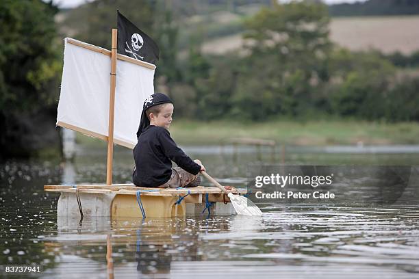boy playing on raft in the water - alleen jongens stockfoto's en -beelden