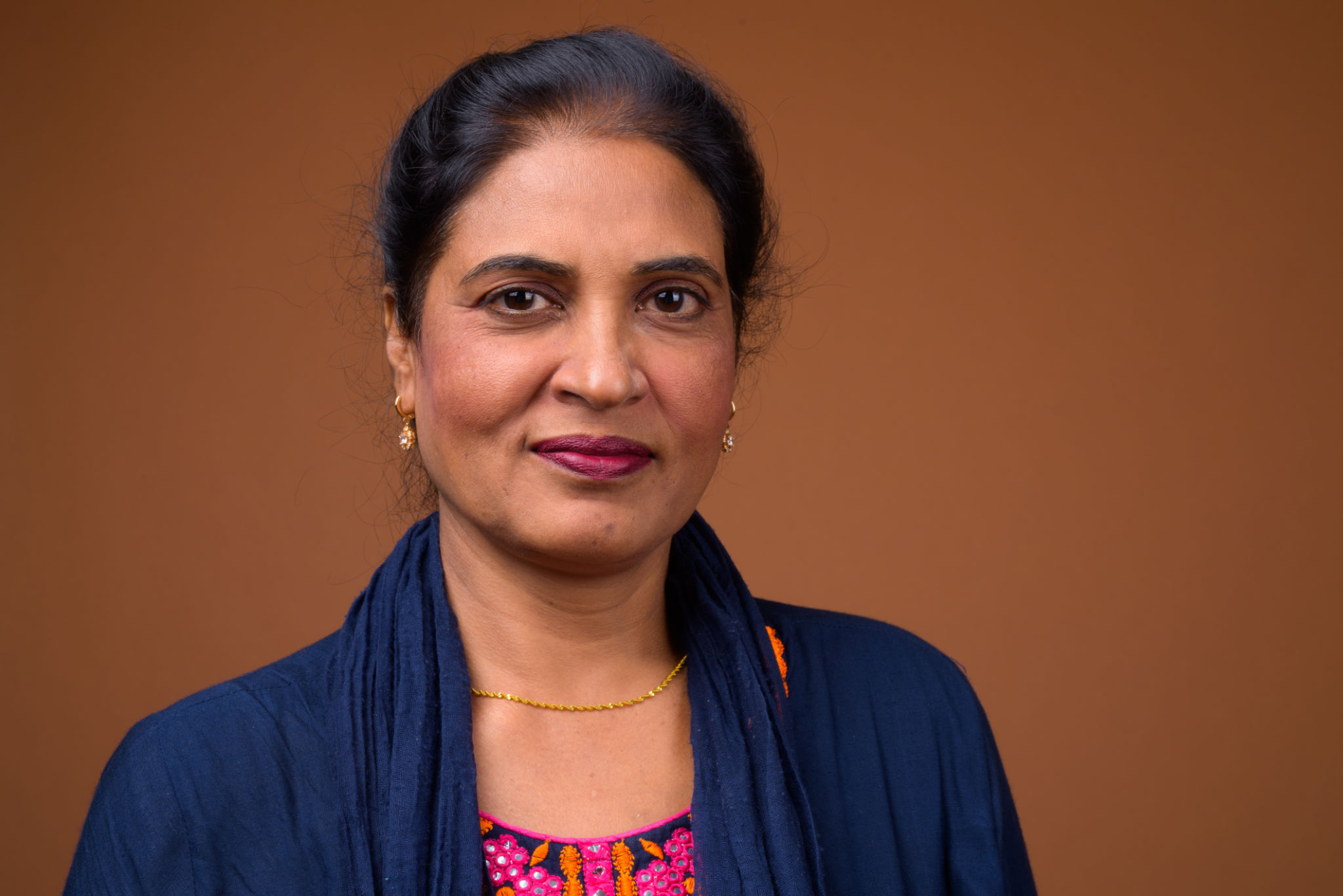 Studio shot of mature beautiful Indian woman against colored background Studio shot of mature beautiful Indian woman against colored background