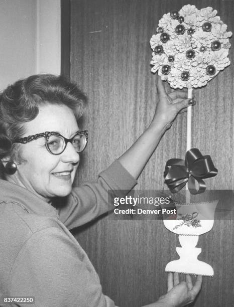 Mrs. R.G. Dameron hangs a silver pine cone doorway tree that will be sold at the bazaar. Items will include card baskets, bathroom accessories,...