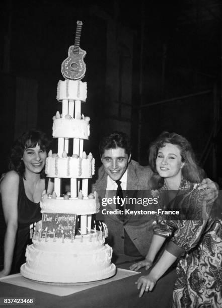 Bernadette Lafont, Danik Patisson et Sacha Distel devant son gâteau d'anniversaire à Paris, France, le 30 janvier 1960.