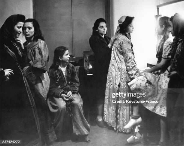 Jeunes actrices de la troupes d'amateurs du 'Théâtre du Peuple' dans leur loge avant d'entrer en scène, à droite, de profil, la vedette de la troupe...