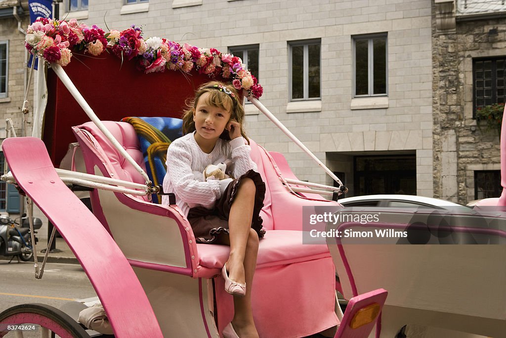 Young girl sitting in horse drawn carriage