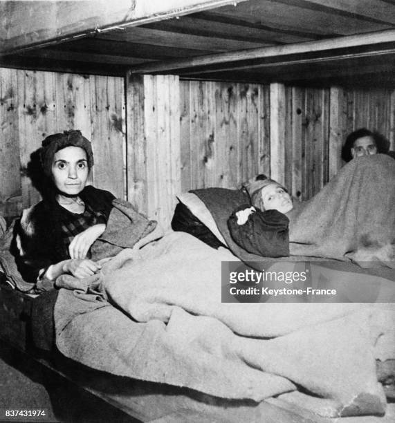 Une femme squeletique, le regard effaré, repose encore en vie sur un lit, à Penig, Allemagne en 1945.