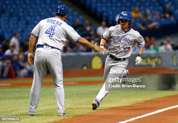 Norichika Aoki of the Toronto Blue Jays celebrates with third base coach Luis Rivera after hitting a home run off of pitcher Chris Archer of the...