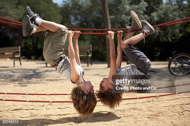 twins hang from structure in park - twins boys stockfoto's en -beelden