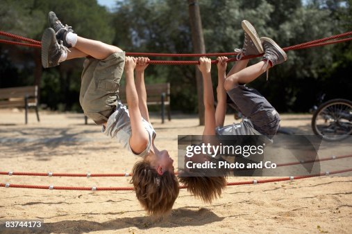 Twins hang from structure in park Twins hang from structure in park
