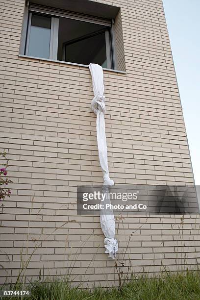 sheets tied to create a rope out of a window - sheets stockfoto's en -beelden