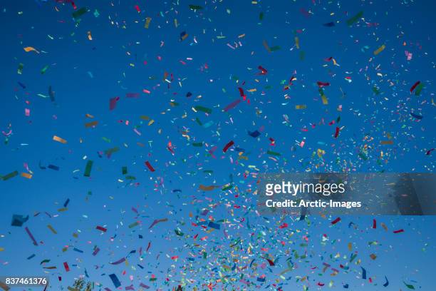 colorful confetti against a blue sky - celebration confetti stock-fotos und bilder