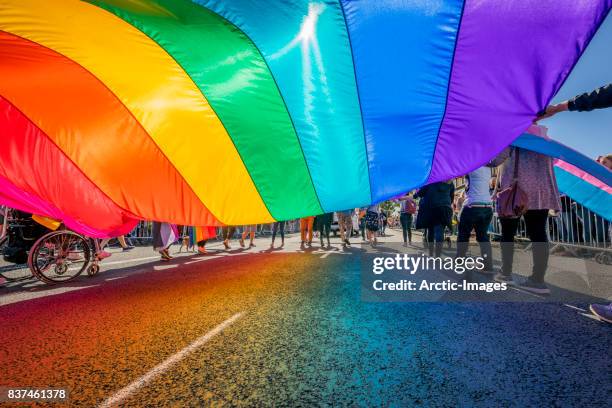 gay pride parade-people marching with a large flag, reykjavik, iceland - roze zaterdag stockfoto's en -beelden