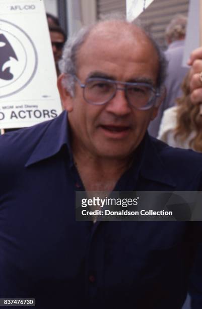 Actor Ed Asner smokes a cigarette as he holds a SAG and AFTRA Actors On Strike picket sign in circa 1980 in Los Angeles, California.