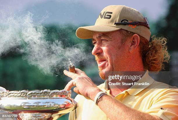 Miguel Angel Jimenez of Spain smokes a cigar as he takes a look at the trophy after the pro - am of the UBS Hong Kong Open at the Hong Kong Golf Club...