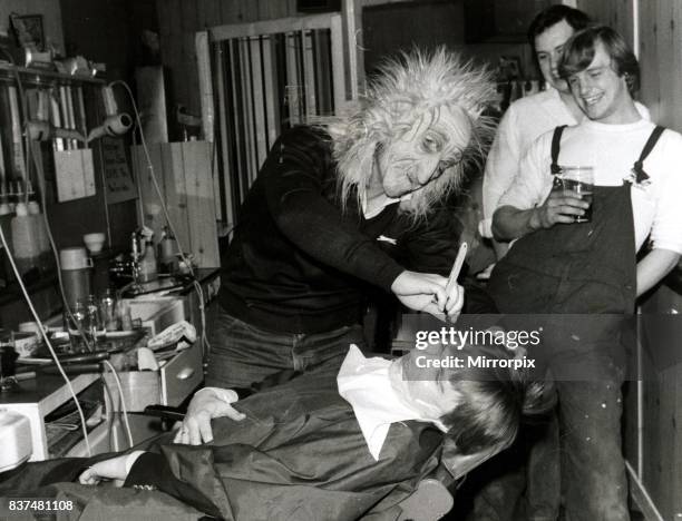 Customer sits in the barbers chair having his faced shaved by a man in a mask at Steve Chatworth's barber shop in East london May 1980.
