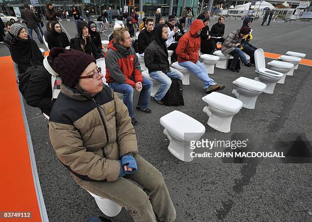 Guests sit on ceramic toilets as they attend a press conference by various sanitation and hygiene concerns in front of Berlin's central railway...