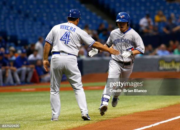 Norichika Aoki of the Toronto Blue Jays celebrates with third base coach Luis Rivera after hitting a home run off of pitcher Chris Archer of the...