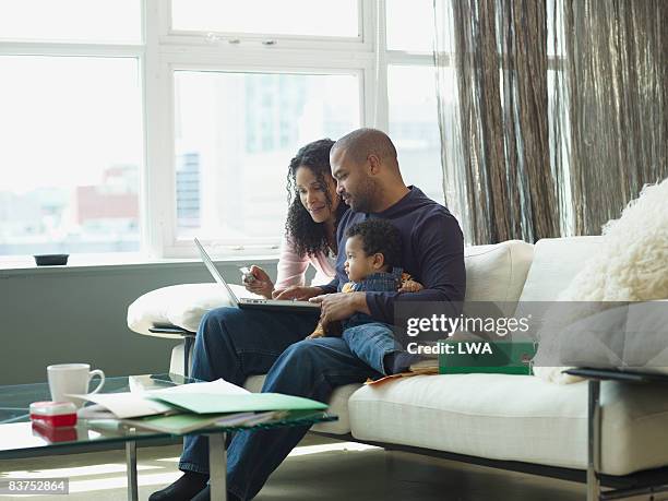 family shopping online - family on couch with mugs stock-fotos und bilder