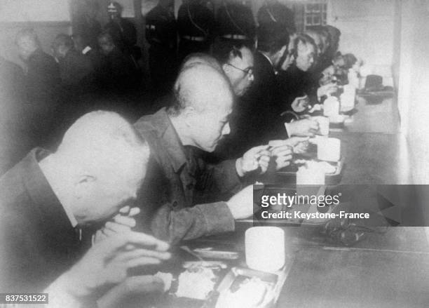 Les accusés mangent à la gamelle, on reconnait Tojo , à Tokyo, Japon en 1946.