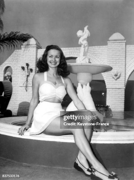 Actrice américaine Noel Neill posant assise devant une fontaine, aux Etats-Unis en 1946.