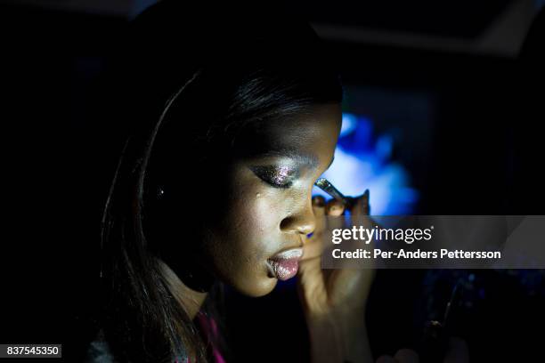 Ugandan model Aamito Lagum gets her make-up done before a show with the South African designer label Fabiani on August 19, 2017 in Mall of Africa...