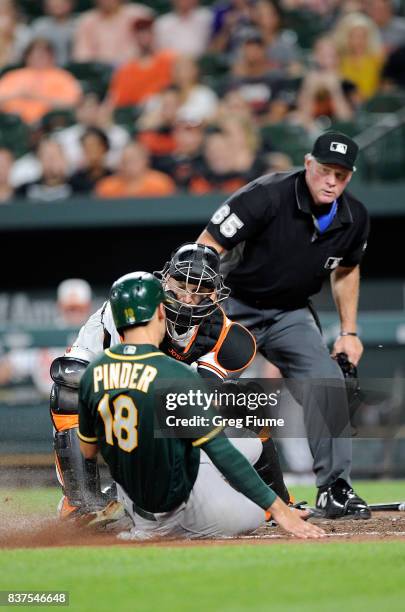 Caleb Joseph of the Baltimore Orioles tags out Chad Pinder of the Oakland Athletics in the eighth inning at Oriole Park at Camden Yards on August 22,...