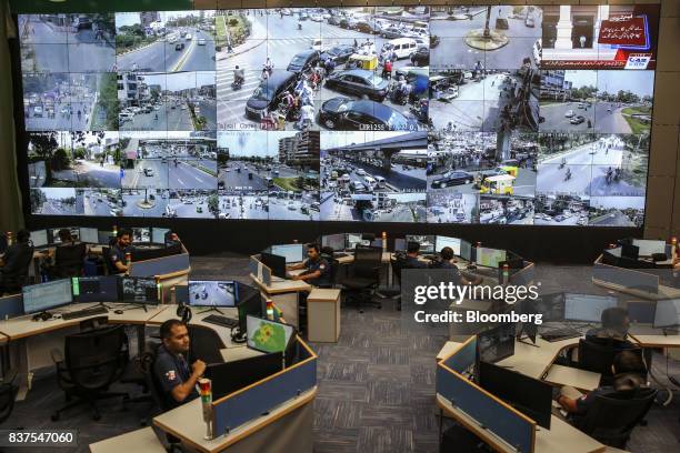 Police officers observe live video feeds from various locations around the city on monitors at the Punjab Police Integrated Command, Control and...