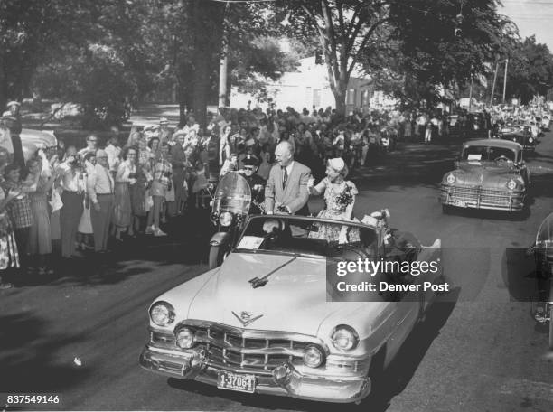 Parade Route - General and Mrs. Eisenhower wave from the open seat of their car to some of the thousands of Coloradans who lined the route from...