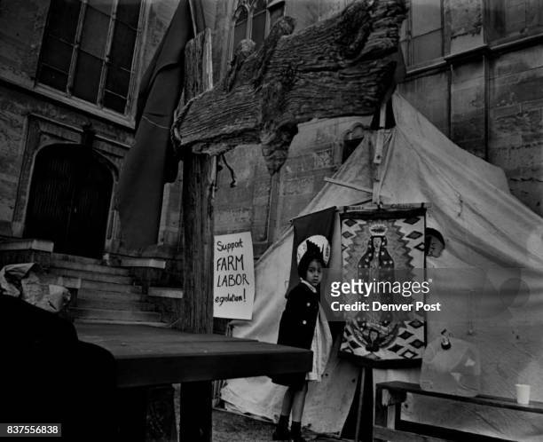 Rosie Herrera of 361 Elati St. Looks over Tent in Visit to Church Standing at the end of the table is a crude cross and behind Rosie is the flag of...