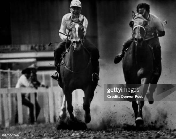 Riders in midst of horse race a feature of rodeo. No, it isn't a polo match, despite the riding helmet on the horseman at left. The tense action was...