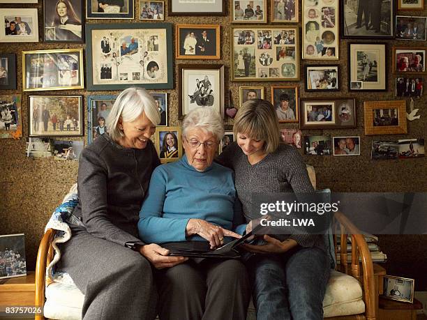 three generations of women looking at photo album - remembrance ストックフォトと画像