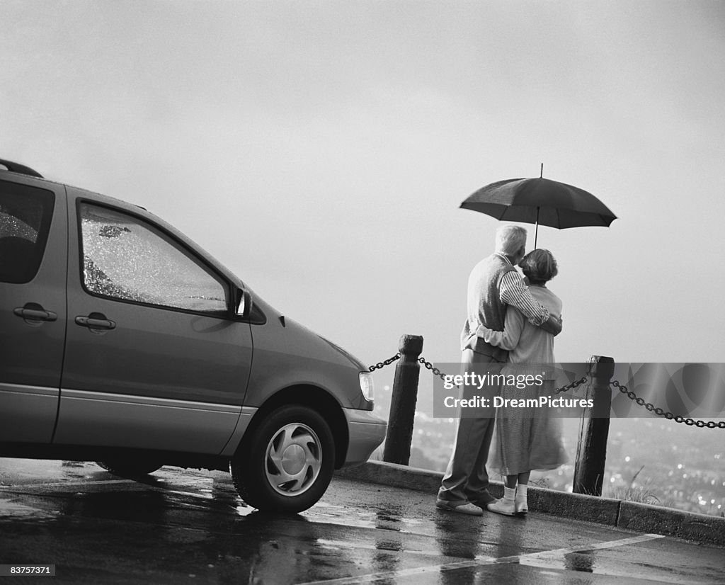 Senior couple under umbrella at scenic outlook