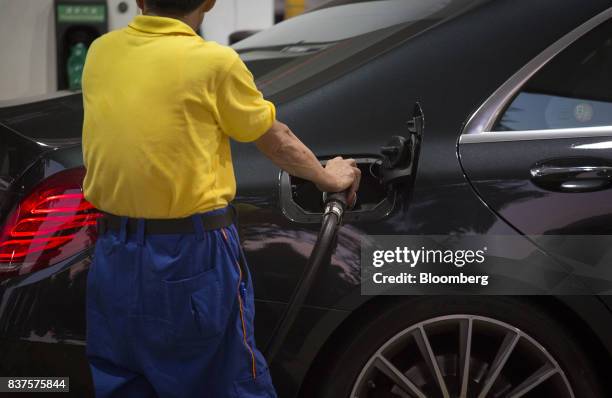 An employee refuels a vehicle at a PetroChina Co. Gas station at night in Hong Kong, China, on Monday, Aug. 21, 2017. PetroChina is scheduled to...