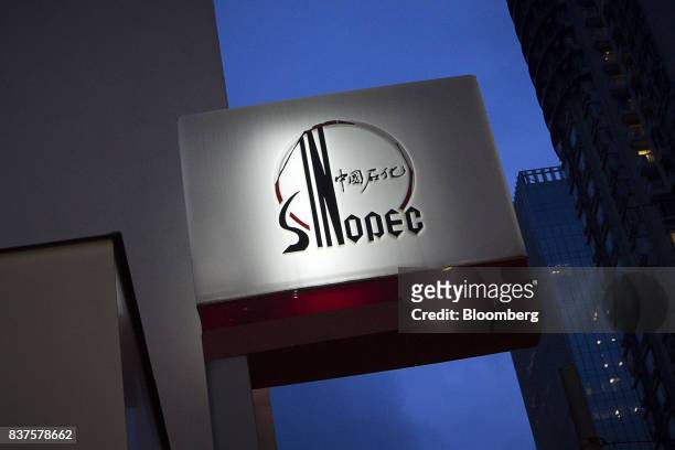 Signage for a China Petroleum & Chemical Corp. Gas station stands illuminated at dusk in Hong Kong, China, on Tuesday, Aug. 22, 2017. Sinopec is...