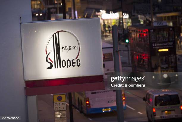 Signage for a China Petroleum & Chemical Corp. Gas station stands next to a road at dusk in Hong Kong, China, on Tuesday, Aug. 22, 2017. Sinopec is...