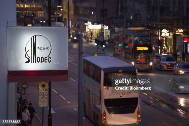 Signage for a China Petroleum & Chemical Corp. Gas station stands illuminated next to a road at dusk in Hong Kong, China, on Tuesday, Aug. 22, 2017....