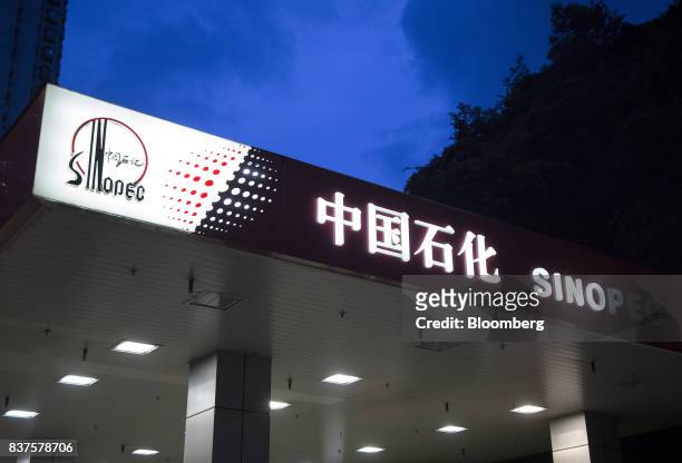Signage atop a China Petroleum & Chemical Corp. Gas station stands lluminated at dusk in Hong Kong, China, on Tuesday, Aug. 22, 2017. Sinopec is...