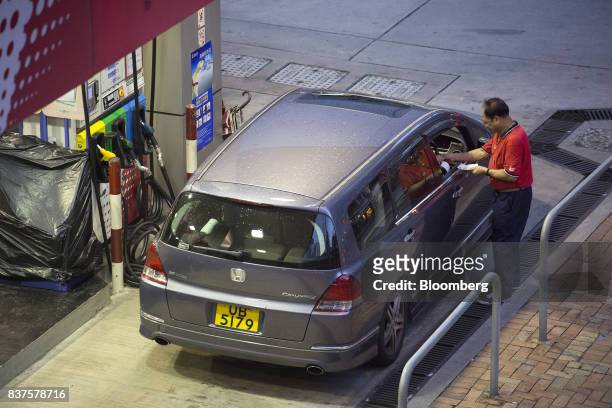 An employee collects payment from a customer after refueling a vehicle at a China Petroleum & Chemical Corp. Gas station at night in Hong Kong,...