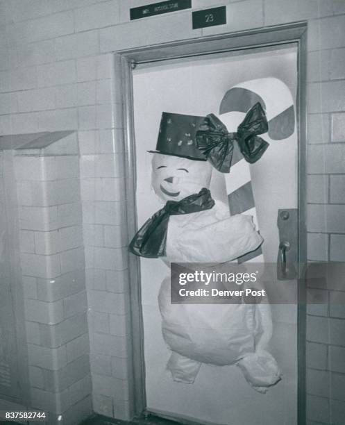 Frolicking, rollicking snowman stuffed with tissue paper and with a carrot nose represents "Frosty" on the door of a classroom at West Junior High...