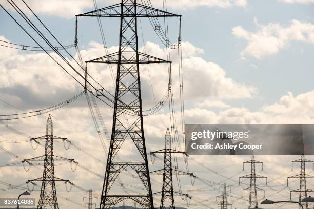pylons carrying electricity from ratcliffe on soar coal fired power station in nottinghamshire, uk with a plane coming in to land at east midlands airport. - electricity pylons stock pictures, royalty-free photos & images