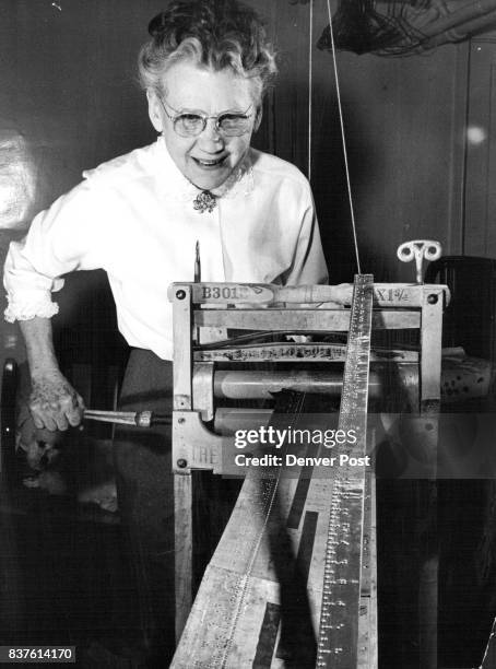 Mrs. IIer O. Watson, group's "inventor," turns out a Braille yardstick on her "press" - an old washing wringer. Credit: Denver Post