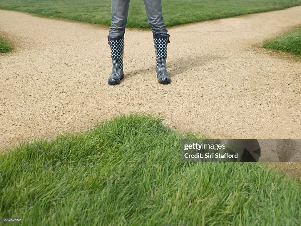 Woman wearing rainboots standing on dirt crossroad