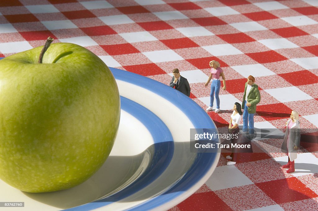 Miniature people looking at apple