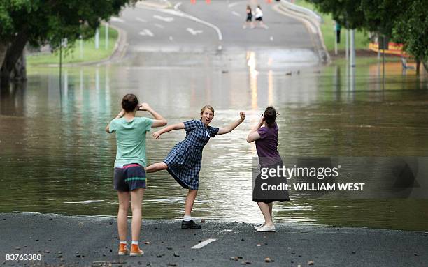 Schoolchildren play in front of a road flooded by the Bremer River in central Ipswich, some 50 kilometres west of Brisbane, on November 20, 2008 as...