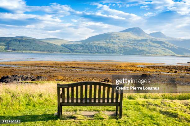 public bench on loch scridain with view to ben more and glen more mountains early morning in summer - isle of mull, inner hebrides, scotland - sea loch stock pictures, royalty-free photos & images