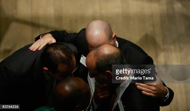 Workers huddle on the floor after the morning bell at the New York Stock Exchange November 20, 2008 in New York City. Stocks were down again in...