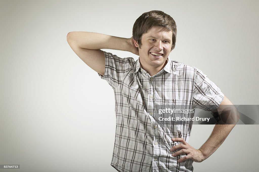 Young man smiling with one hand behind head