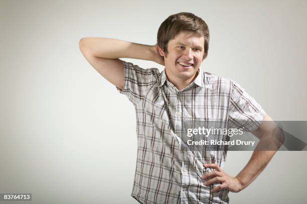 young man smiling with one hand behind head - embarrassment stock pictures, royalty-free photos & images