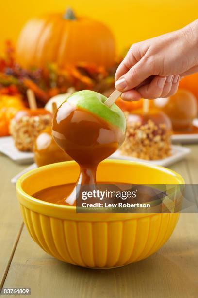 granny smith apple dipping into caramel - caramel apple stock pictures, royalty-free photos & images