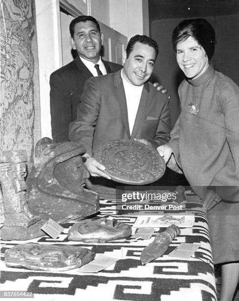 From left are Gilbert Martinez, Sam Sandos and Mrs. Edwin Kahn with a copy of an Aztec calendar at informal opening of center at 935 W. 11th Ave....