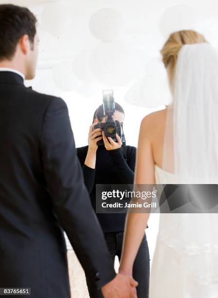 photographer taking photo of bride and groom - fotografo foto e immagini stock